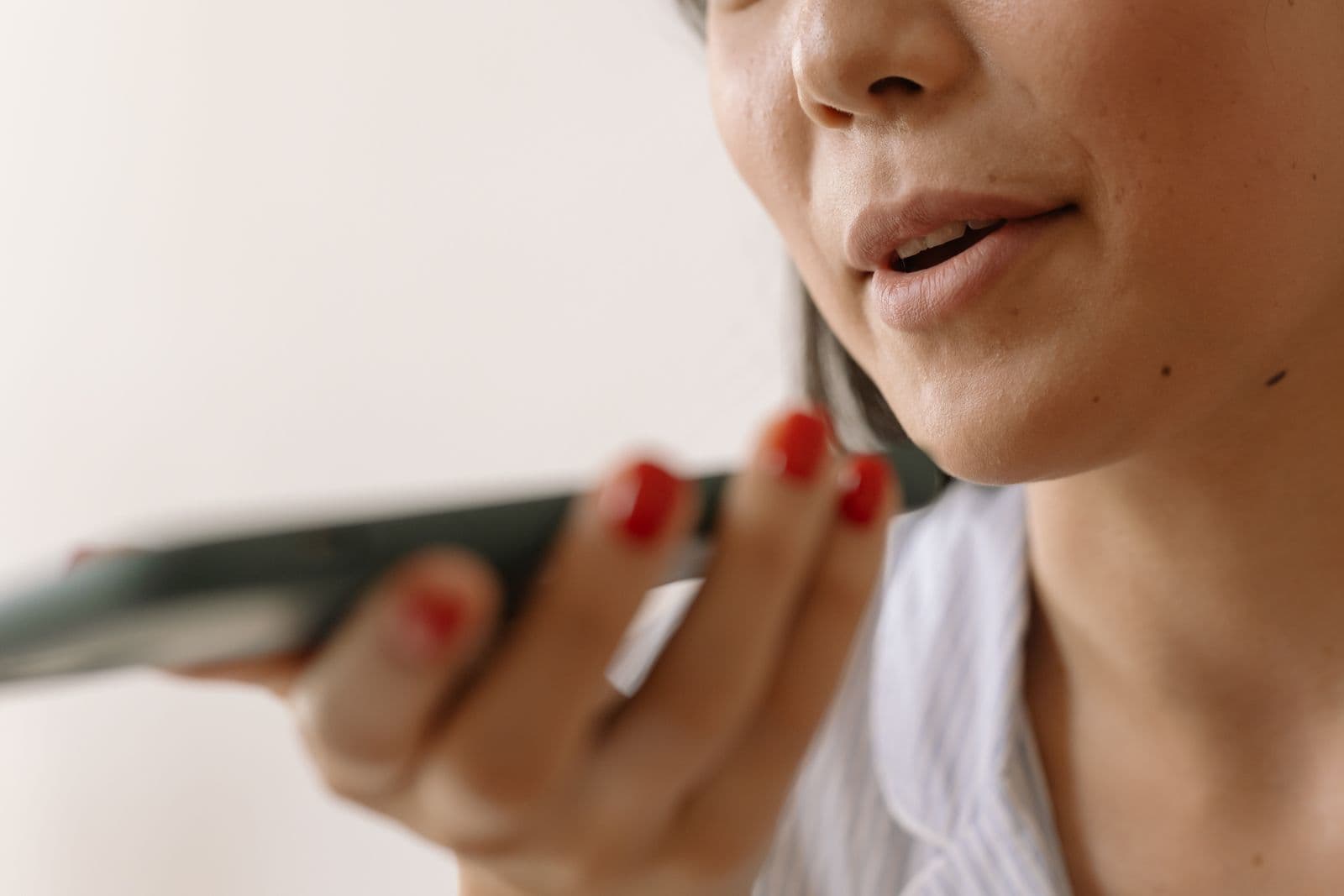 A person speaking into their smartphone's microphone in everyday surroundings